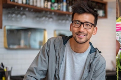 man in grey jacket with glass smiling